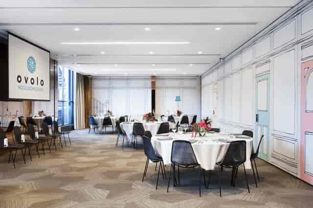 Modern event space at Ovolo Hotels with round tables, ideal for corporate meetings and gatherings.