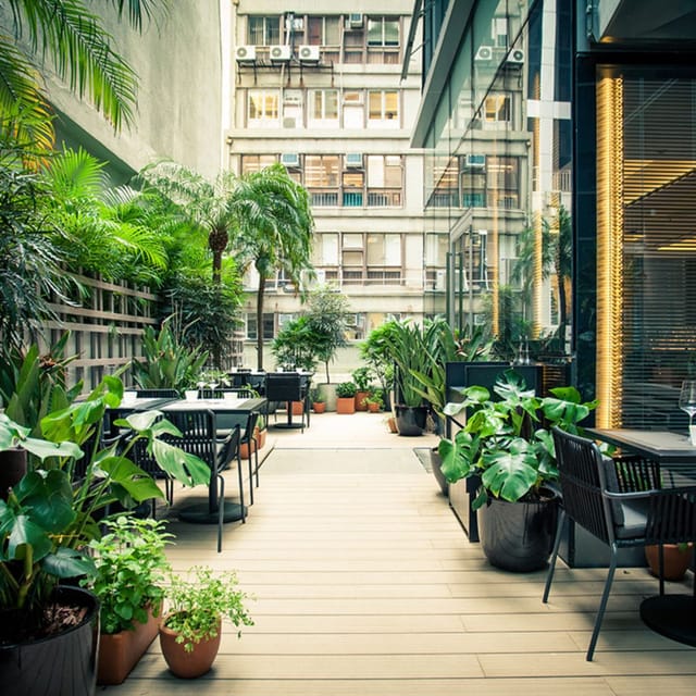 Vibrant outdoor event space with lush greenery and modern furniture for meetings.