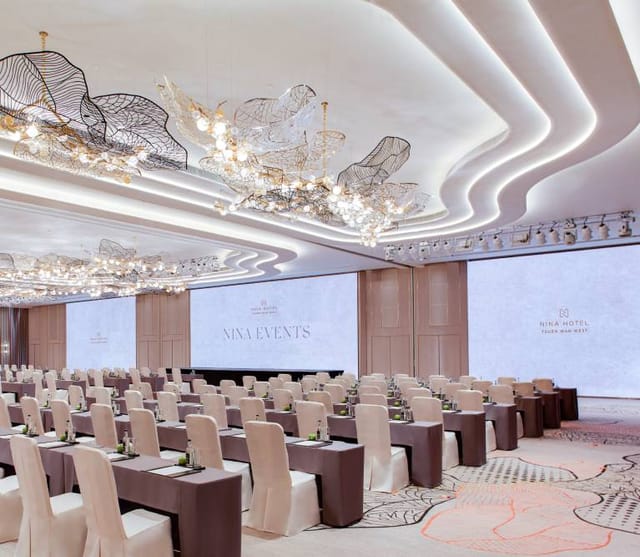 Sky Lounge at Nina Hotel: elegant corporate event space with modern decor and large screens.