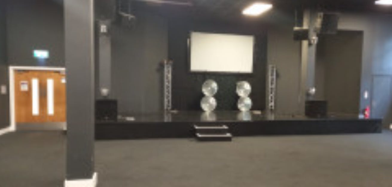 Versatile event space at The Forge with raised stage, ideal for corporate events and presentations.