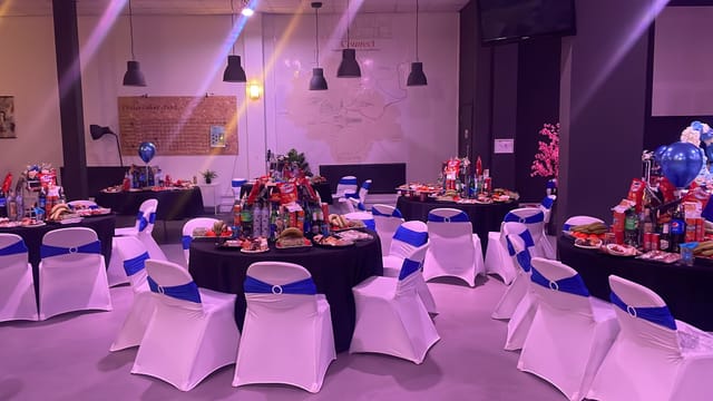 Elegant event space at The Forge, decorated for celebrations with black tables and blue sashes.