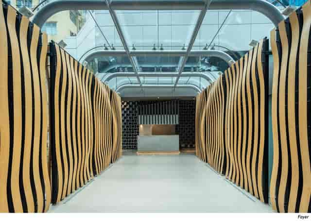 Modern event space with wavy wooden partitions and natural light for gatherings.