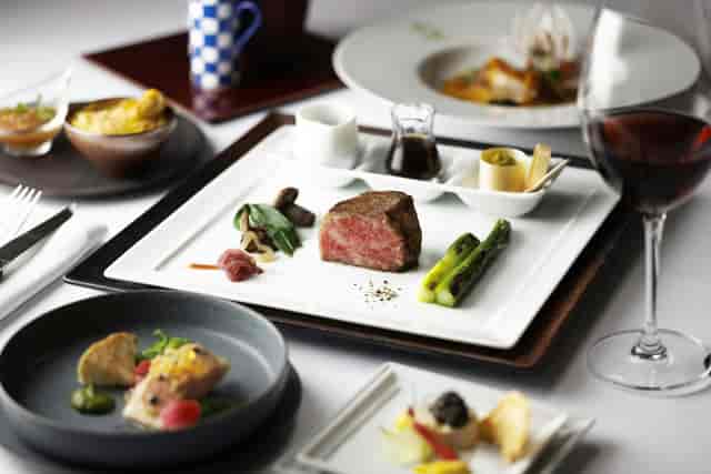 Youko dining at Tokyo Station Hotel with elegant beef dish for corporate events.