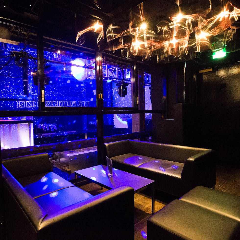 Premium Lounge in WOMB: sleek black furniture, vibrant blue lighting for events.