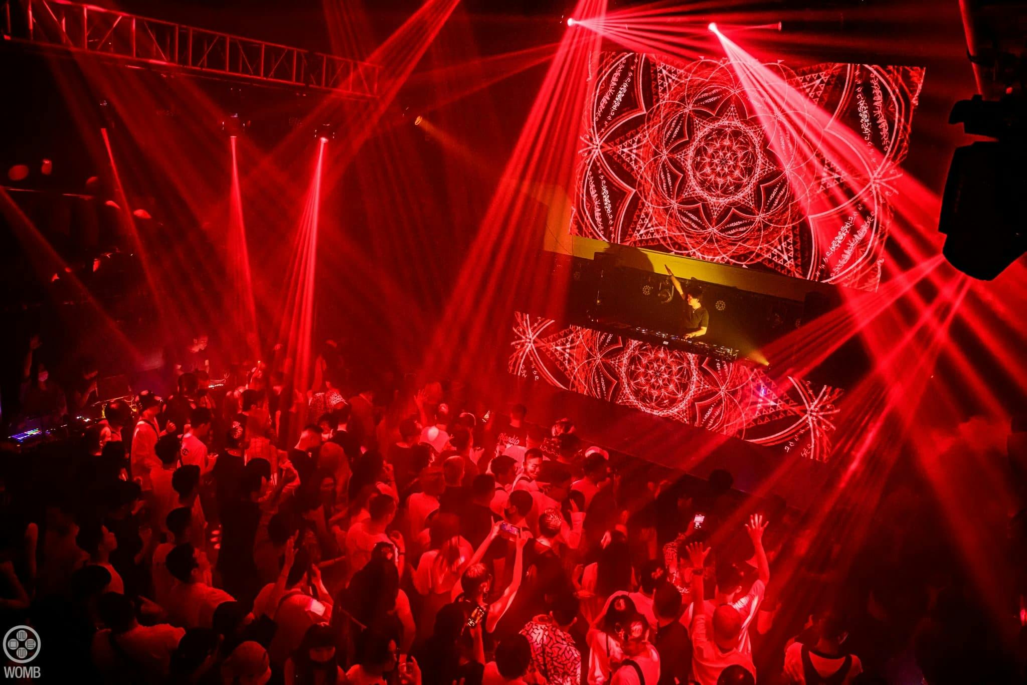 Vibrant event space with DJ setup, red lighting for nightlife gatherings.