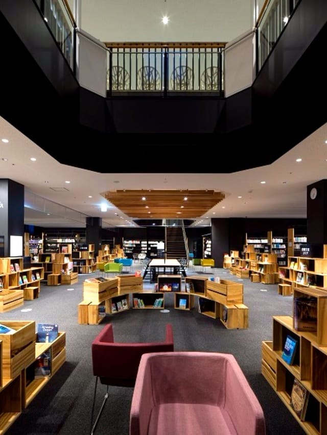 Modern Kōdōkan library with circular wooden bookshelves for workshops and meetings.