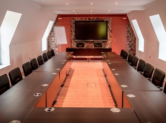 Modern conference room at Salon Polignac with ergonomic chairs and large screen for meetings.