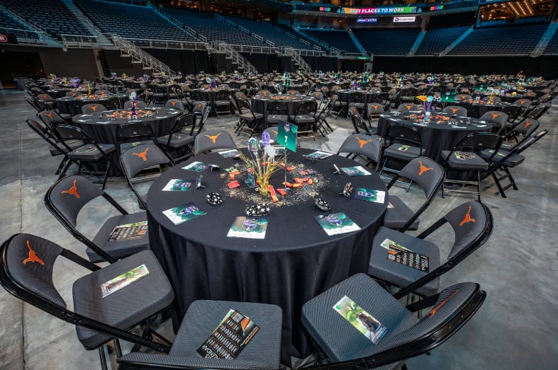 Moody Centre arena floor event setup with round tables and branded chairs.