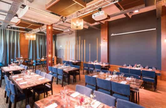 Elegant event space with wooden tables and blue chairs in Palais Kultubrauerei.