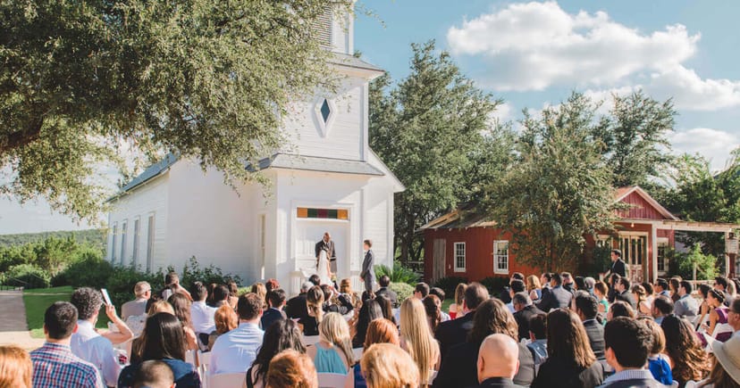 Outdoor wedding ceremony at Star Hill Ranch with charming white chapel and lush greenery.