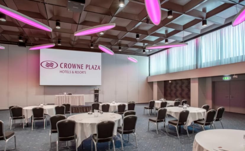 Modern event space at Crowne Plaza Zurich with round tables and pink lighting for meetings.