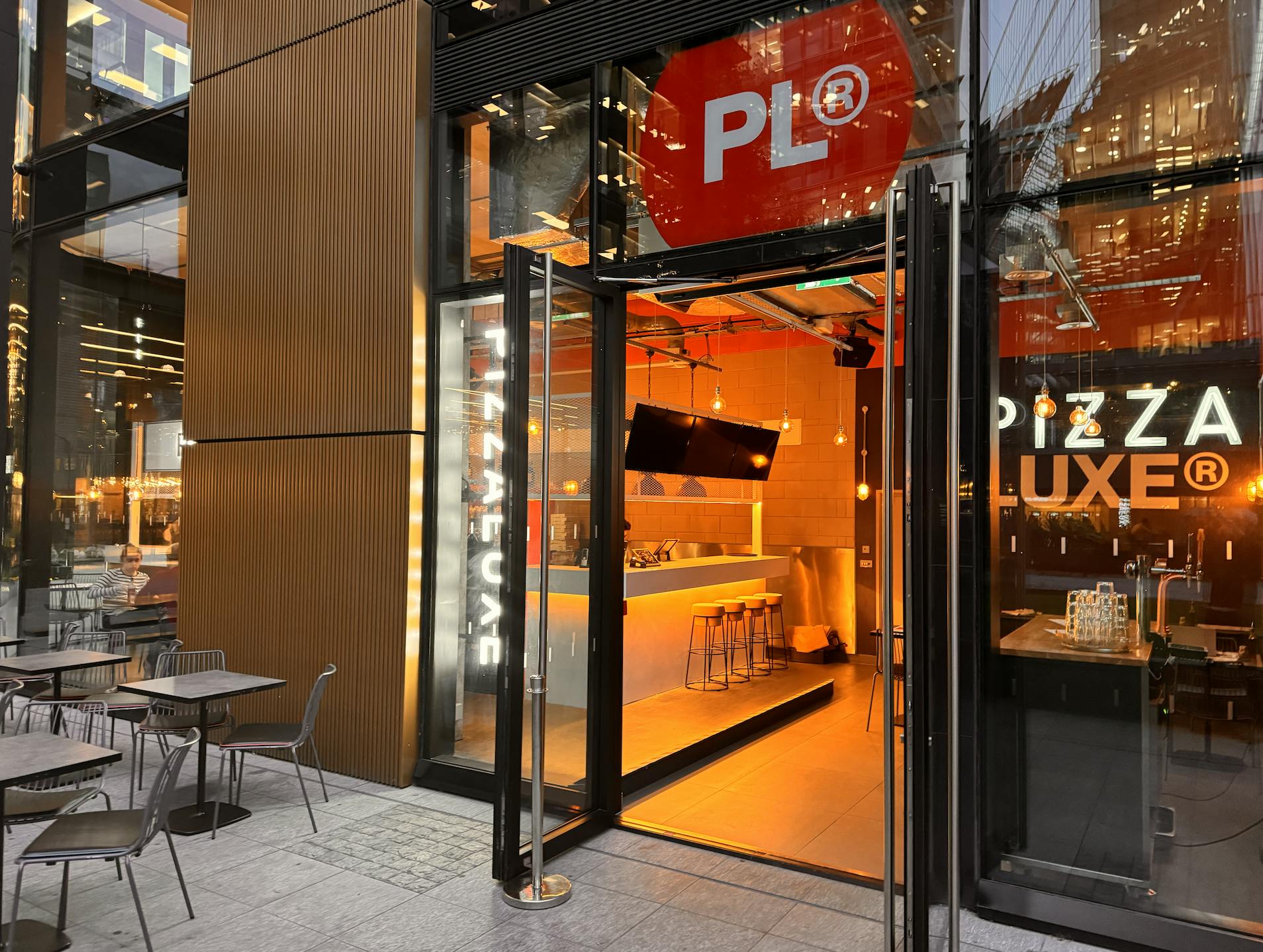 Modern pizza restaurant entrance with outdoor seating for casual networking events.