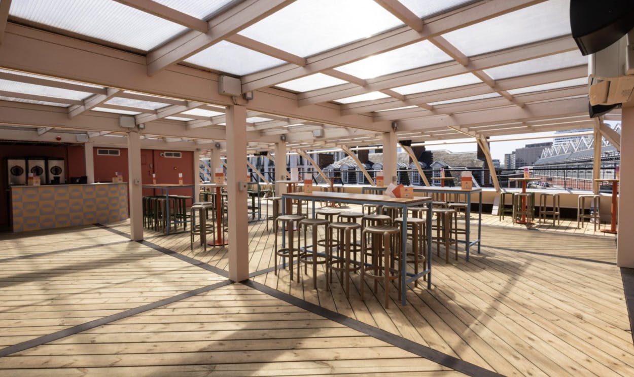Spacious rooftop venue with high tables, ideal for networking events and social gatherings.