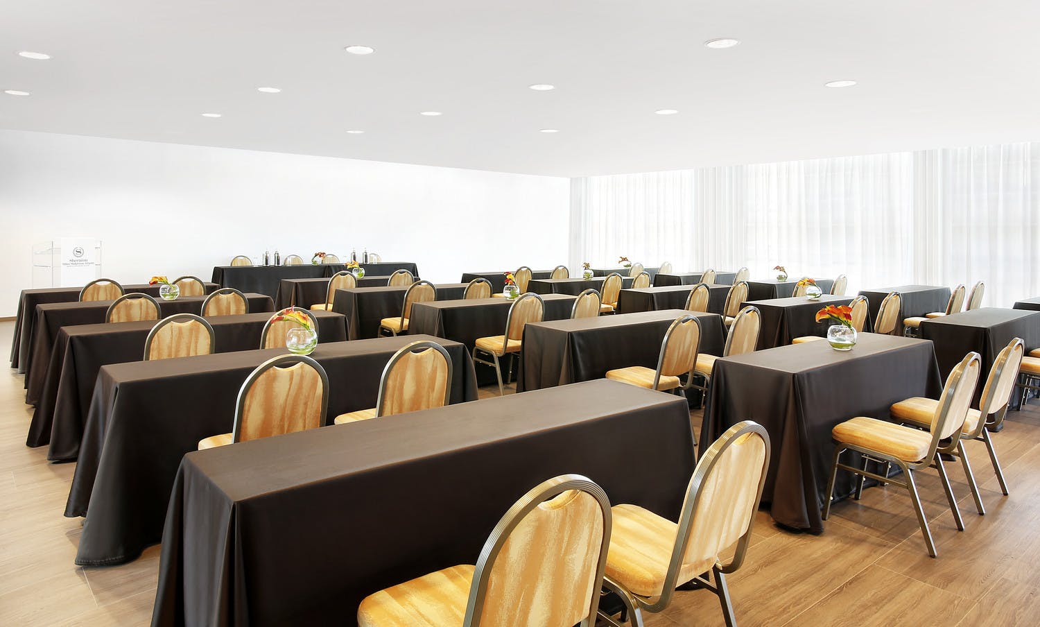 Meeting space at Sheraton Milan Malpensa with black tables and gold chairs for corporate events.