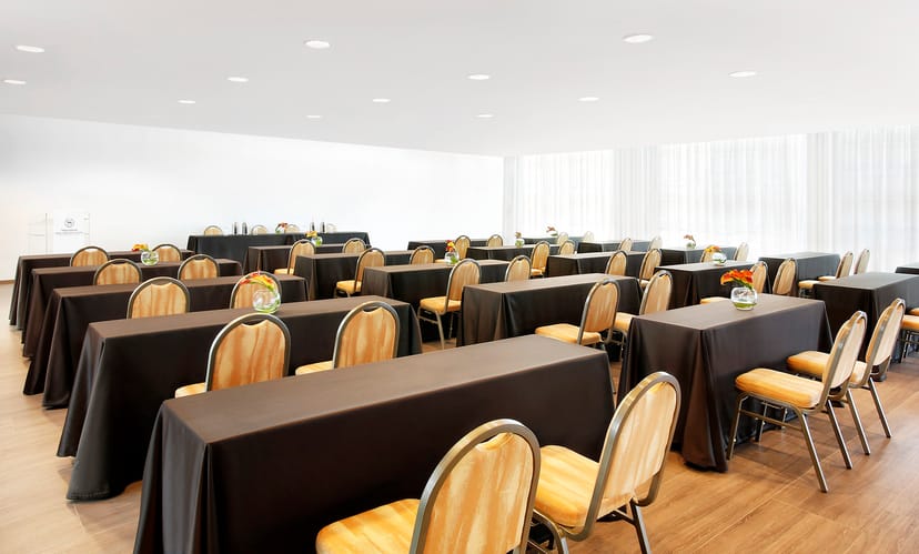 Meeting space at Sheraton Milan Malpensa with black tables and gold chairs for corporate events.