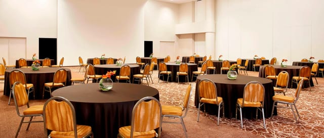 Spacious Sheraton Milan Malpensa event venue with round tables for meetings and banquets.