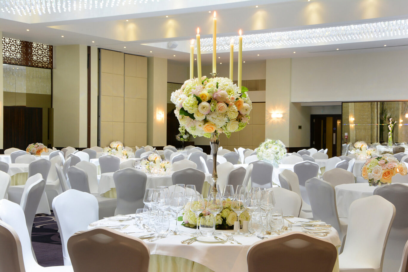 Elegant Grand Ballroom with floral centerpieces, ideal for weddings and corporate events. - Banner
