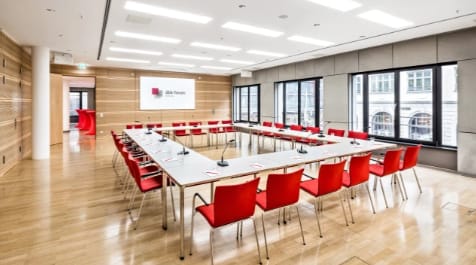 Modern meeting room in dbb forum Berlin with red chairs, perfect for corporate workshops.