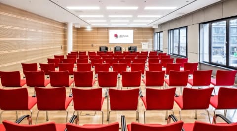 Atrium III IV event space in Berlin with red chairs for presentations and discussions.