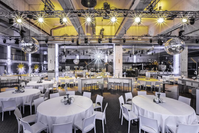 Elegant event space with round tables and disco balls, perfect for corporate events or parties.