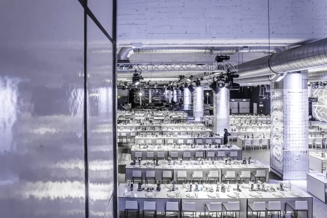 Spacious event venue with elegant tables, perfect for corporate events and formal dinners.