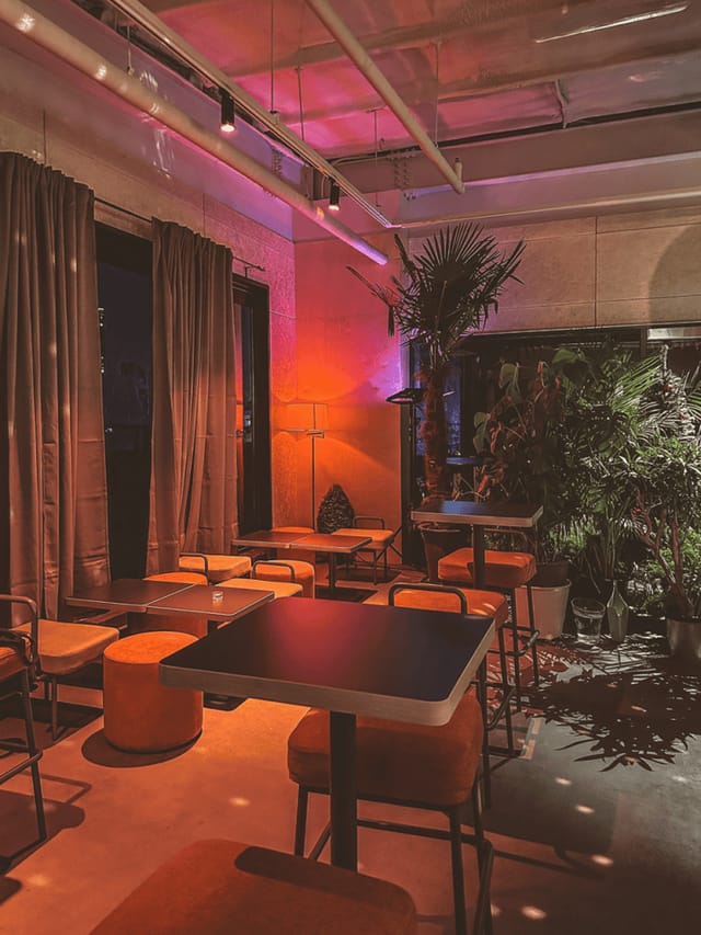 Stylish event space in SFACTORY with warm lighting and lush greenery for gatherings.