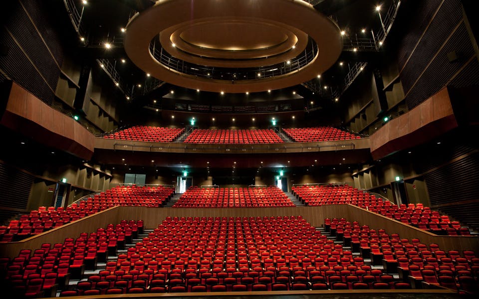 Woori Art Hall auditorium with tiered seating and red chairs for conferences and performances.