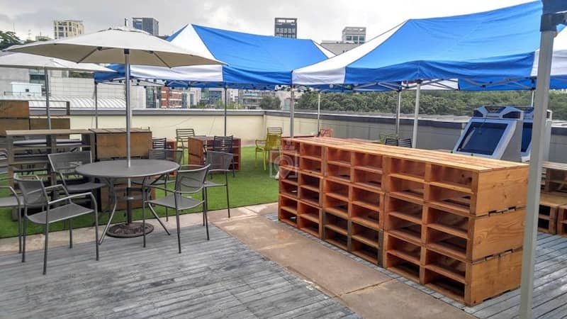 Rooftop event space with blue and white tents, perfect for networking and gatherings.