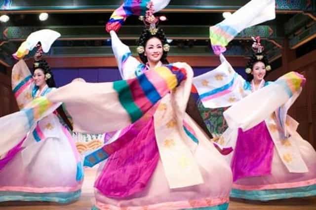 Vibrant dancers in traditional attire at Korea House Folk Theater cultural performance.