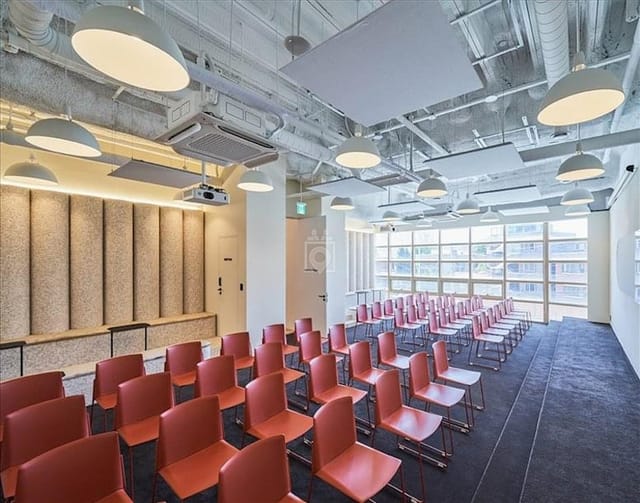 Modern event space with orange chairs, ideal for workshops and corporate meetings.