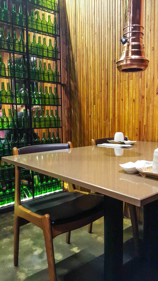 Modern dining setup at Maple Tree House with green glass bottles, ideal for events.
