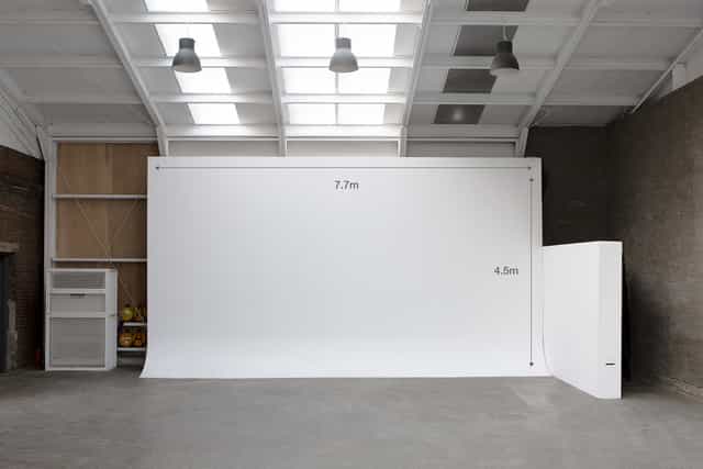 Spacious minimalist event space with white backdrop for corporate meetings and artistic events.