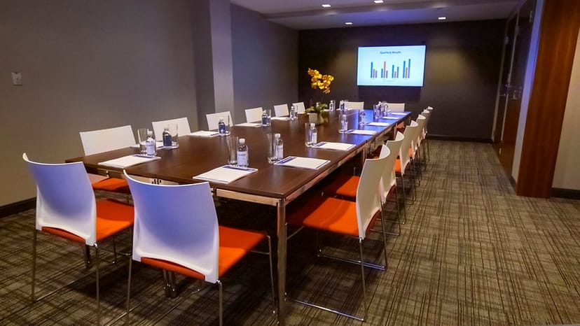 Blake Room at The Godfrey Hotel Boston, modern meeting space with vibrant orange chairs.