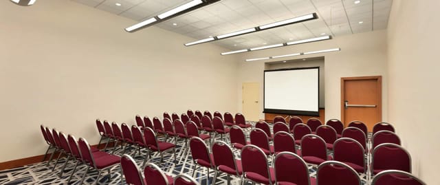 Conference room with burgundy chairs and projection screen for meetings or workshops.