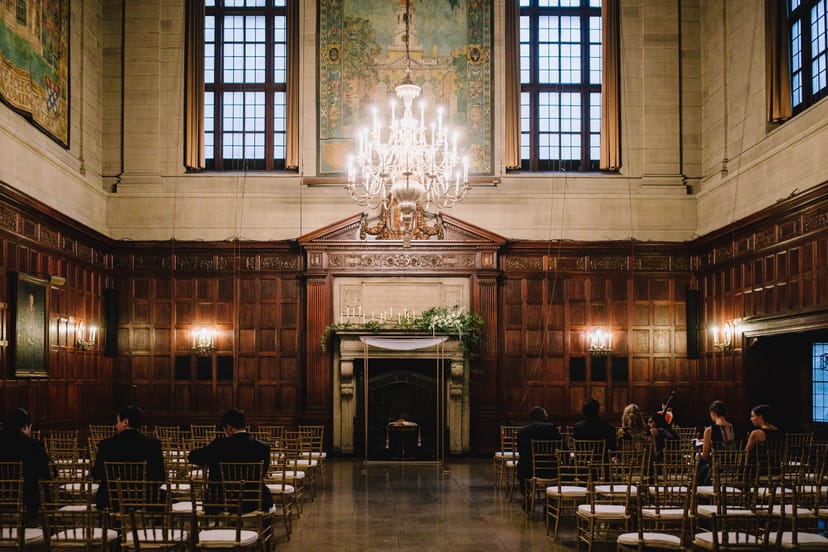 Elegant event space at Harvard Club of Boston with wood paneling and chandelier.