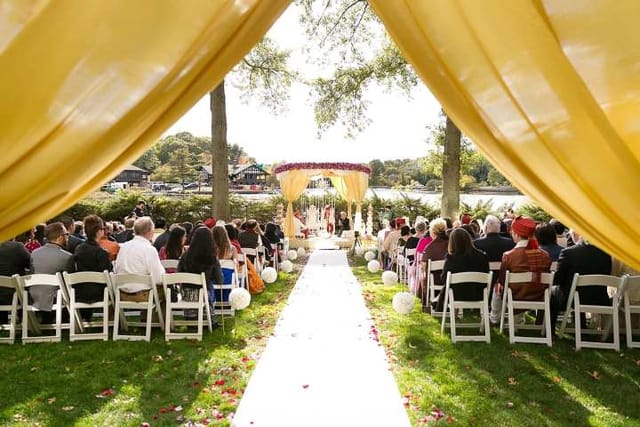 Outdoor wedding ceremony at Riverside Lawn, Boston Marriott Newton with yellow drapery.