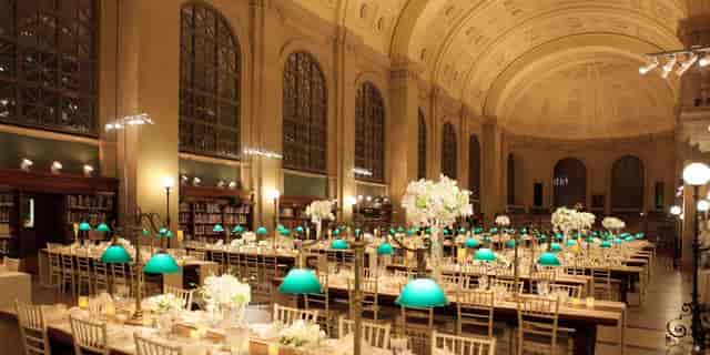 Elegant event space in Boston Library with floral centerpieces and turquoise lamps.