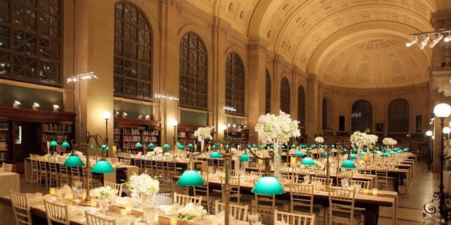 Elegant event space in Boston Library with floral centerpieces and turquoise lamps.
