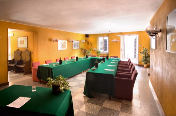 Sala Faggio meeting room with green tablecloths, perfect for workshops and conferences.