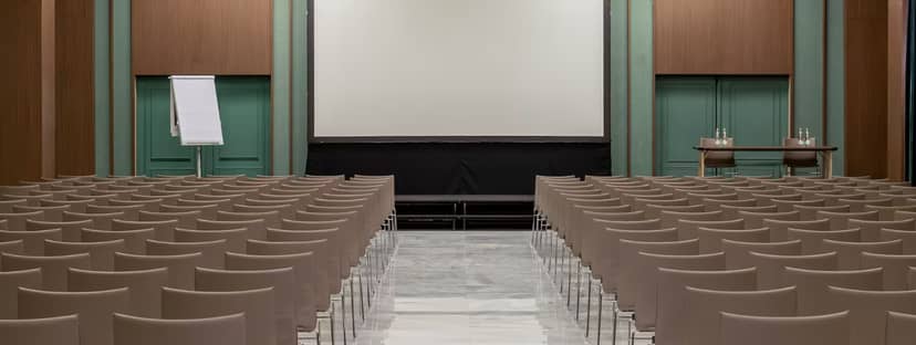 Conference room setup with beige chairs and blank screen for presentations in Melia Milano.