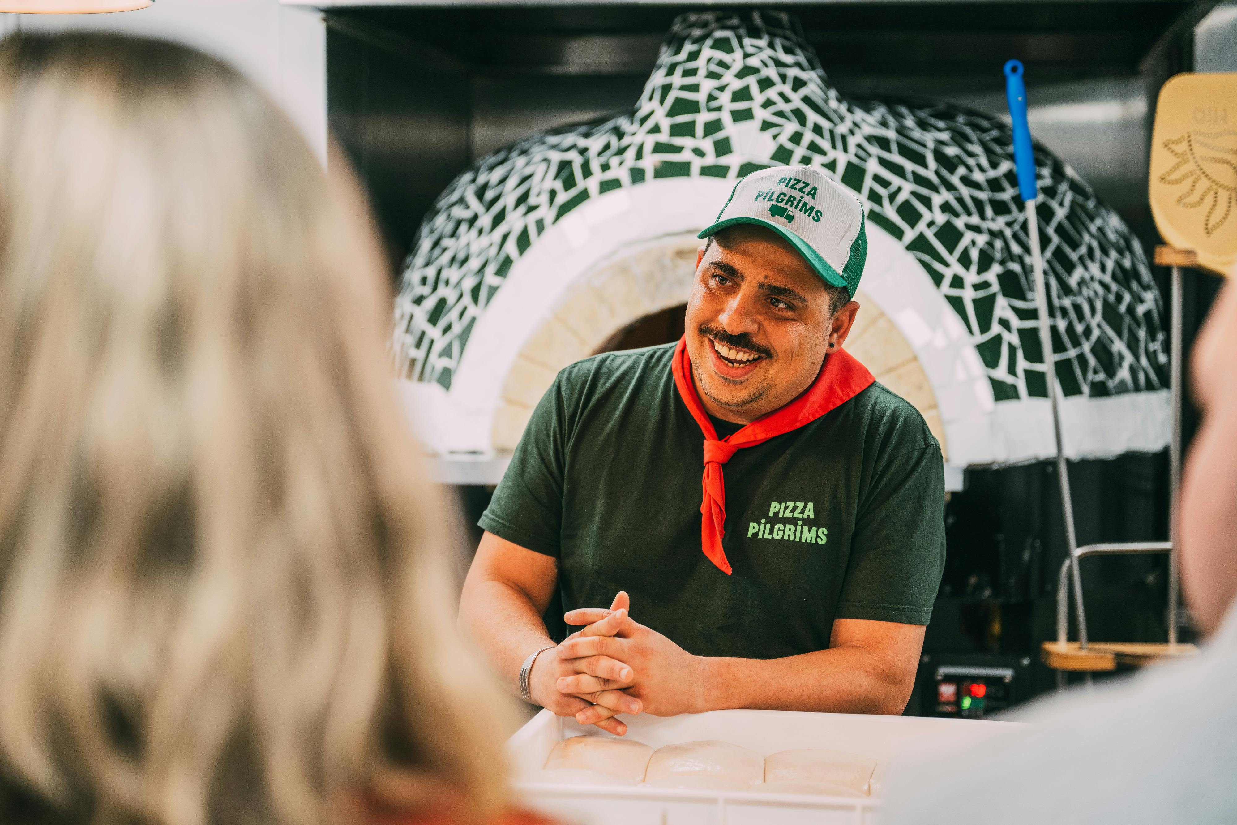 Pizza chef at Dough It Yourself event with rustic oven for interactive dining experience.