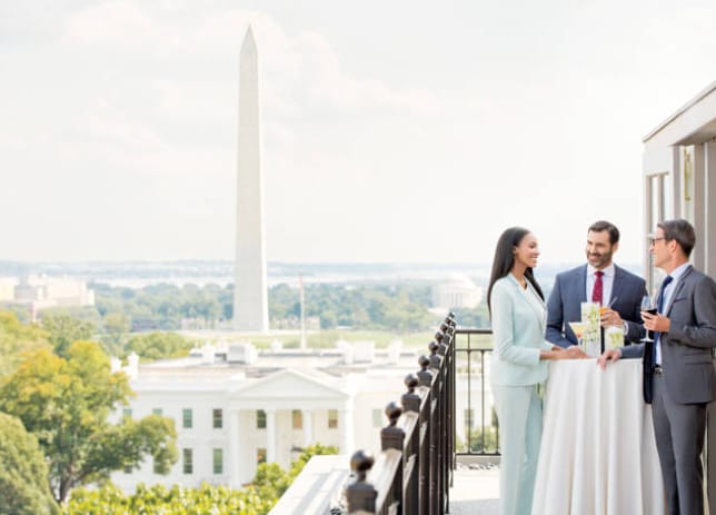 Sophisticated networking event on balcony with Washington Monument view, ideal for corporate gatherings.