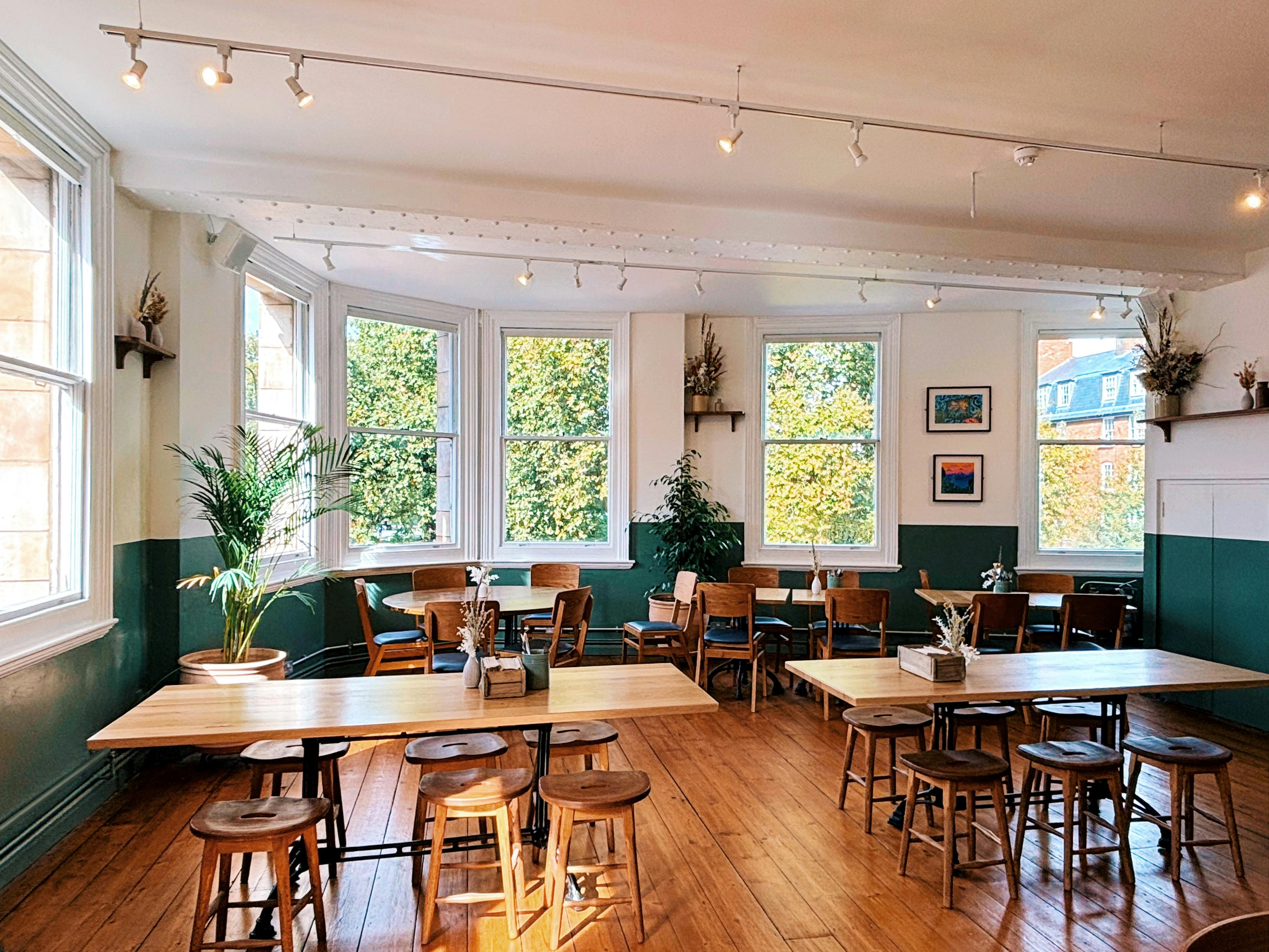 Bright event space with wooden tables, perfect for meetings and gatherings at Gladwell's Deli.