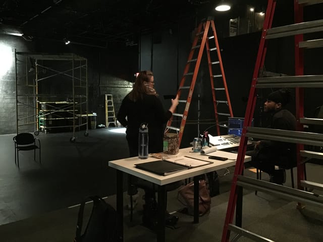 Black Box Theatre setup with ladders, showcasing event preparation and teamwork.