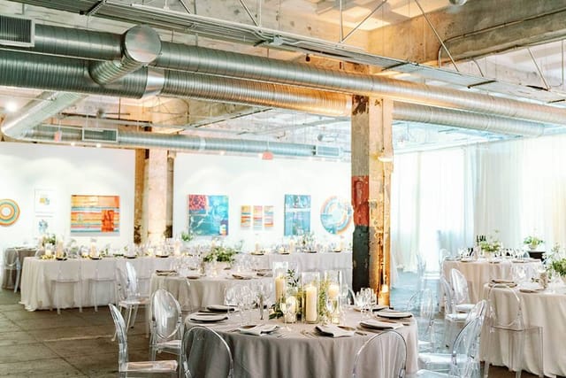 Art gallery event space with round tables, ideal for weddings and corporate gatherings.