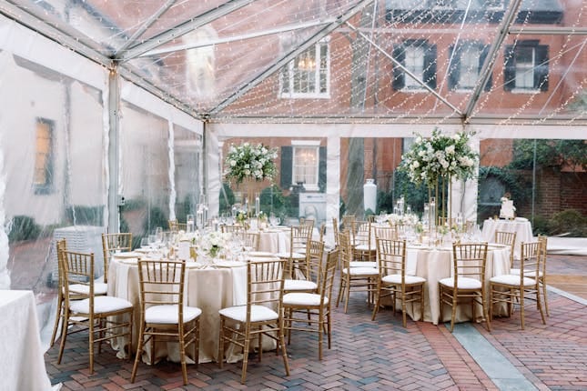 Elegant outdoor wedding venue with round tables under a clear tent at Decatur House.