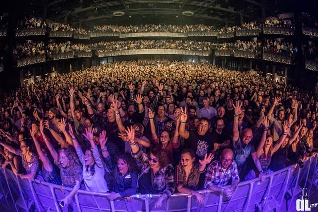 Packed concert hall with enthusiastic crowd, showcasing event engagement and atmosphere.