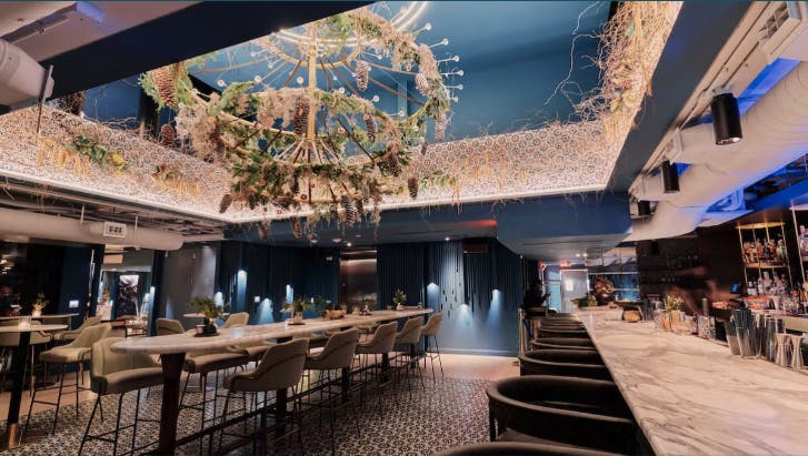 Stylish rooftop event space with modern bar and greenery chandelier for gatherings.