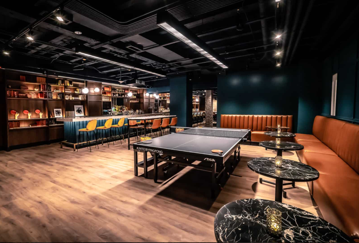 Modern lounge with sleek bar and ping pong tables for networking events.
