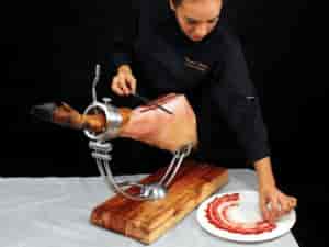 Chef slicing ham at upscale event venue Sala Sambara 81 for interactive culinary experience.